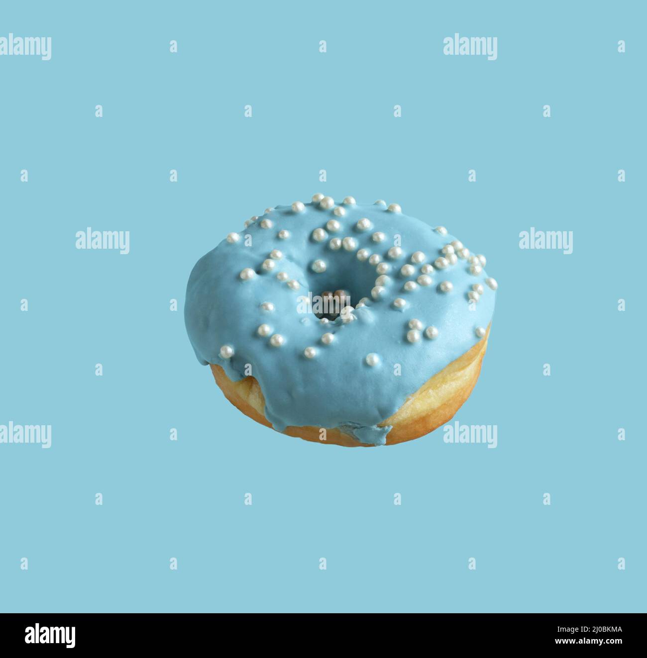 Donuts covered with pale blue icing and sprinkled with pearl sugar beads on a light blue background. Closeup Stock Photo