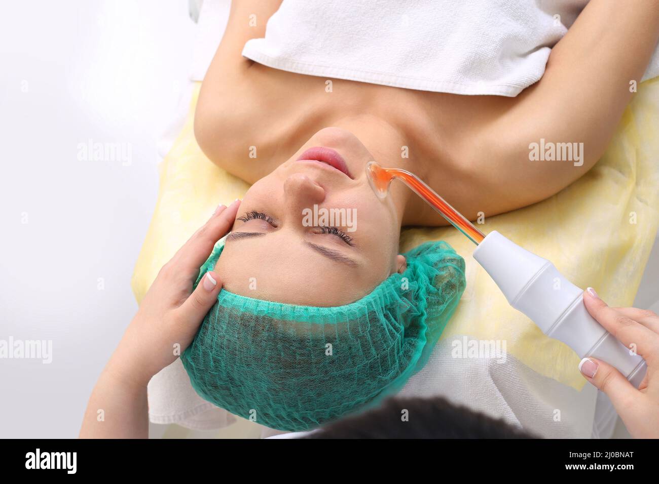 Receiving electric darsonval facial massage procedure. Stock Photo