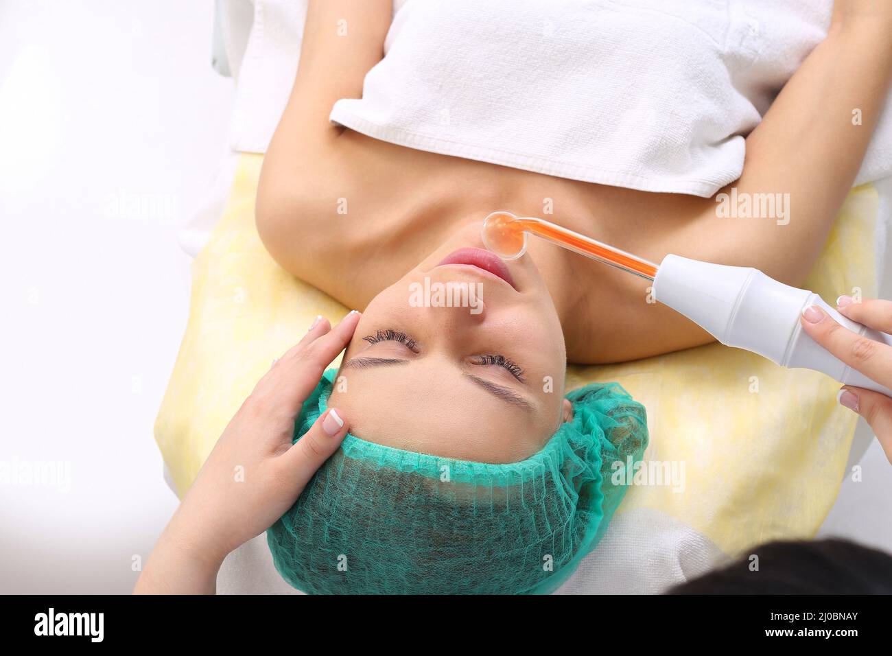 Receiving electric darsonval facial massage procedure. Stock Photo