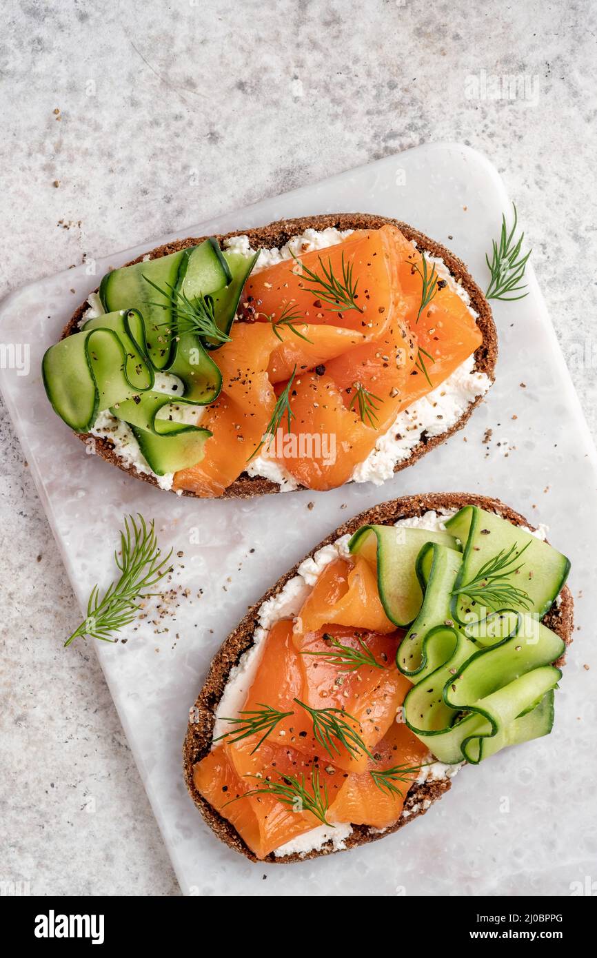 Rye bread open sandwiches with salted salmon and cucumber on a white