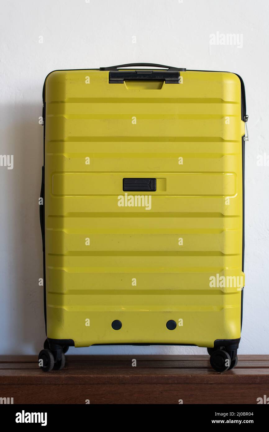 Yellow suitcase against a white wall.  Stock Photo