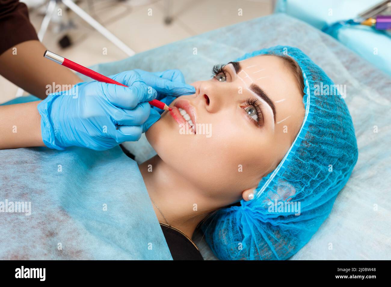 Cosmetologist making permanent makeup on woman's face Stock Photo