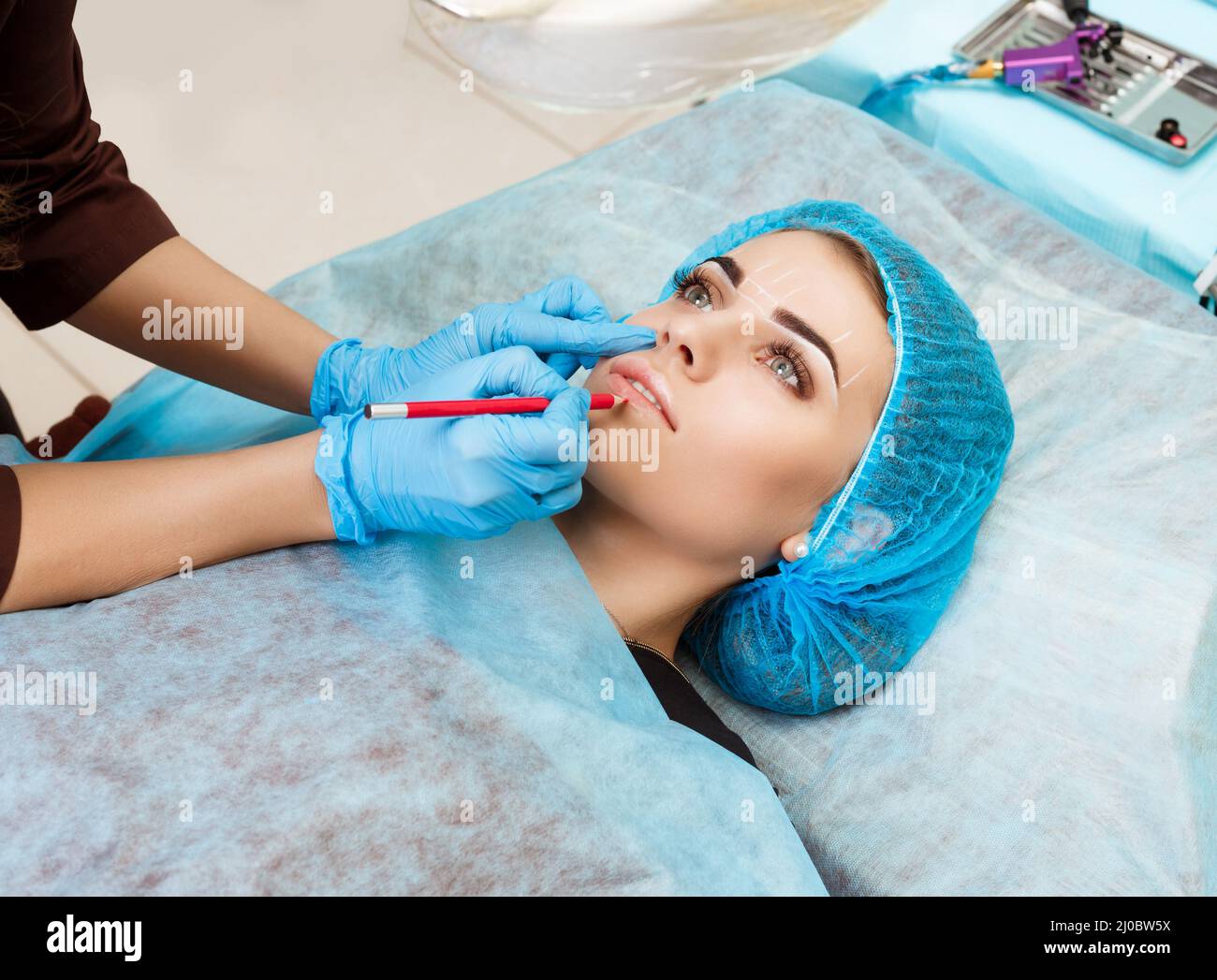 Cosmetologist making permanent makeup on woman's face Stock Photo