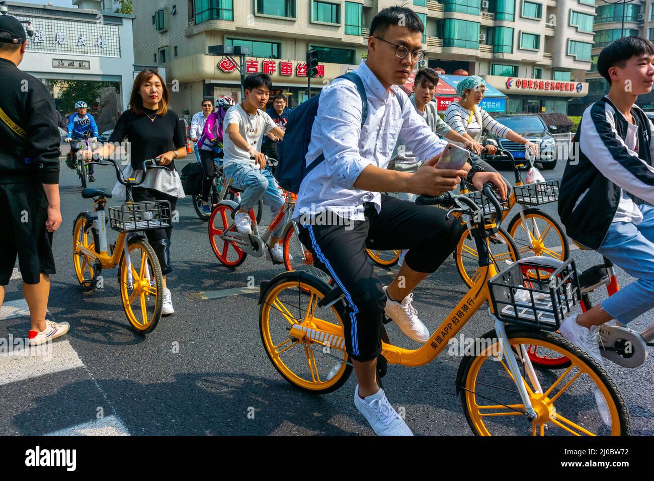 Hangzhou, China, Crowd Young Chinese People Using Bicycles on Street, chinese man riding bike city, urban public space mobility ecology, responsible tourism Stock Photo