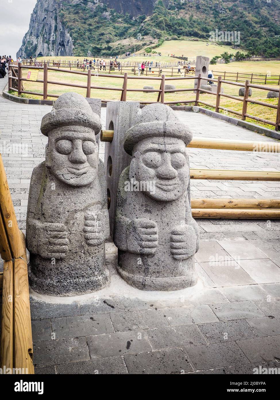 Twin Jeju idols (Dolharubang, the grandfather stones ) in Seongsan Ilchulbong (Sunrise Peak), one of the UNESCO nature tourism s Stock Photo