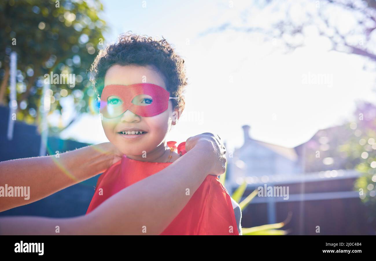 Moms dressing me up like my favourite superhero. Shot of an adorable little boy wearing a superhero costume while playing outdoors. Stock Photo