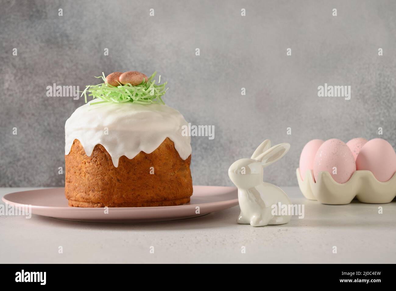 Homemade traditional Easter cake, easter rabbit, pink eggs on gray background. Stock Photo