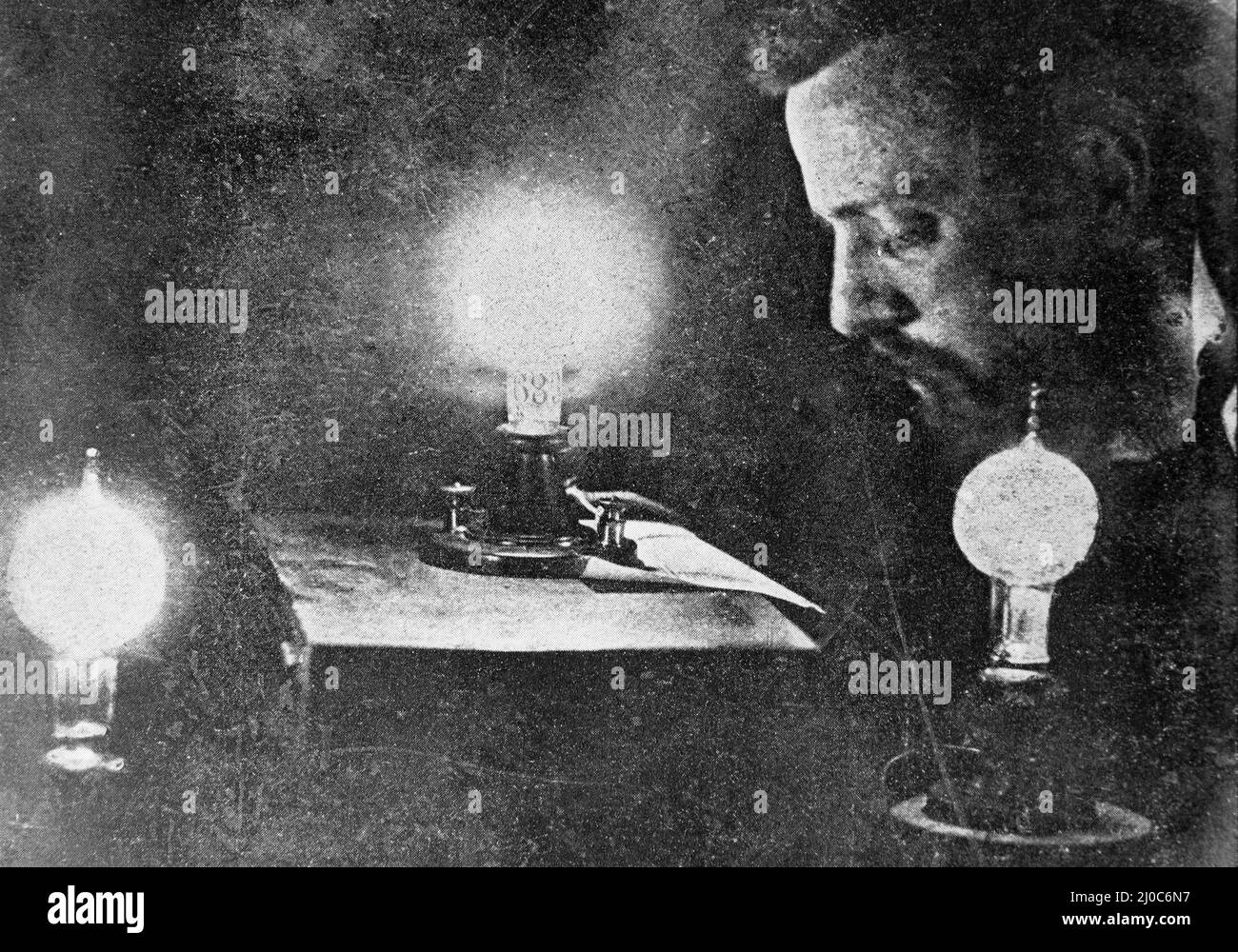 Reading by the light of the first lamp at Thomas Edison's Laboratory; Black and white photograph taken circa 1878s Stock Photo