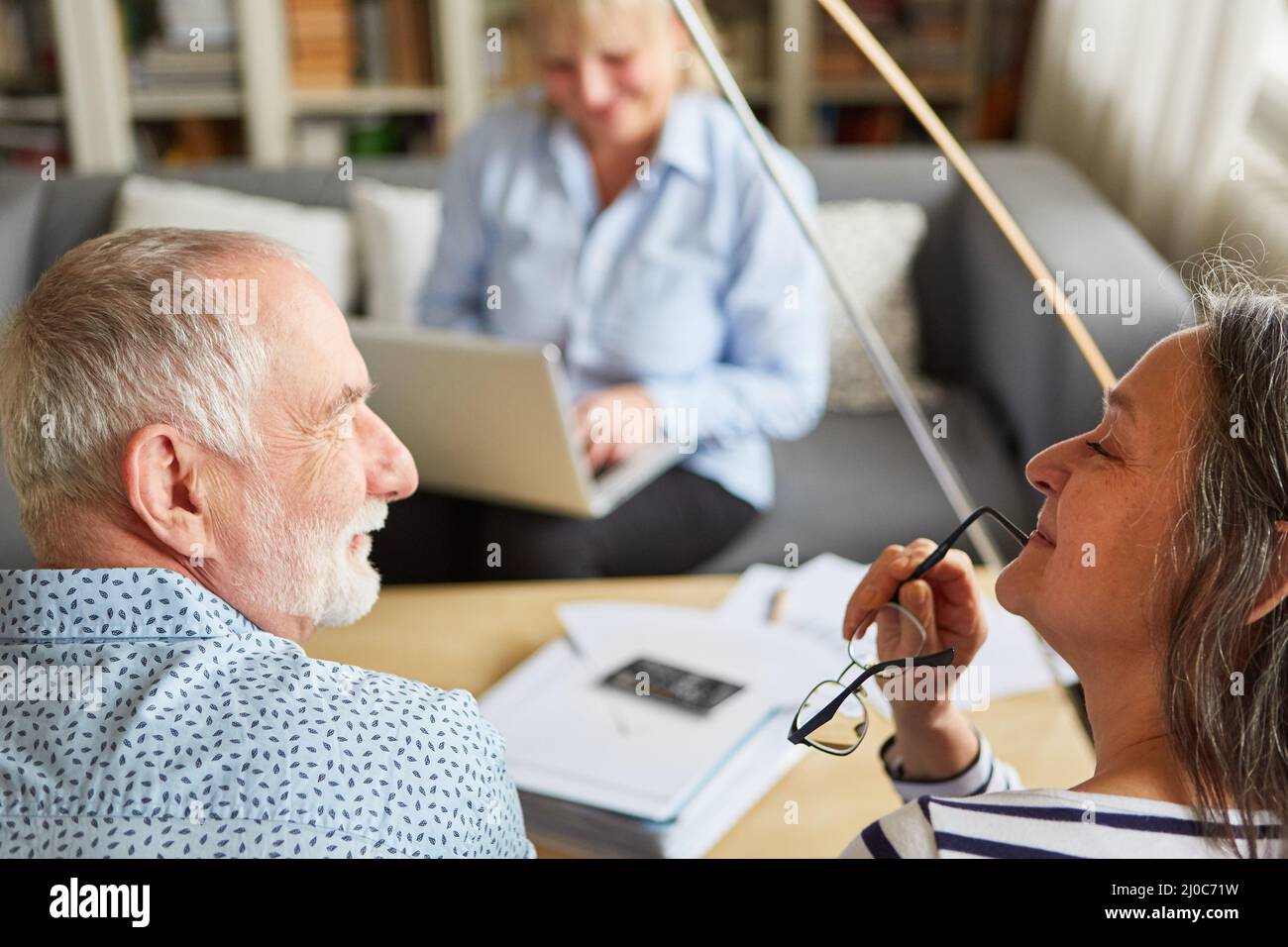 Retired senior couple thinking about securing retirement savings with consultant in background Stock Photo
