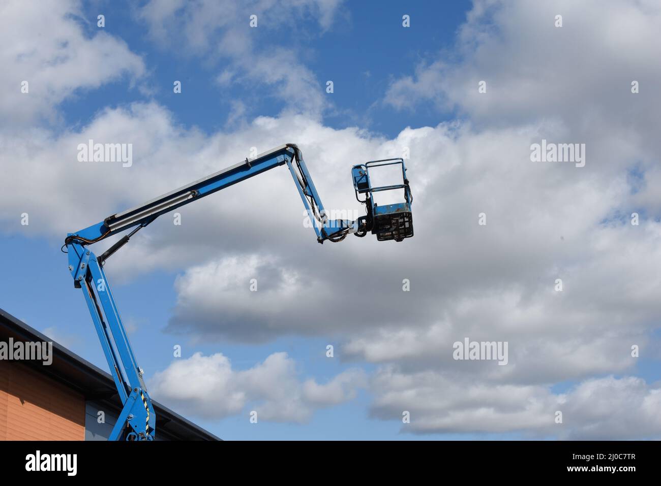 Cherry picker lift platform with telescopic arm on a building site to reach high up in construction industry Stock Photo