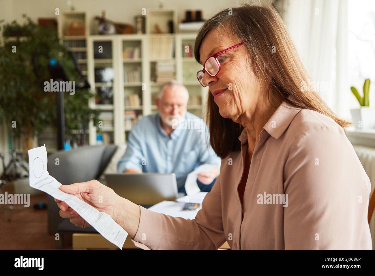 Elderly woman looking at bill or receipt for accounting and tax return at home Stock Photo