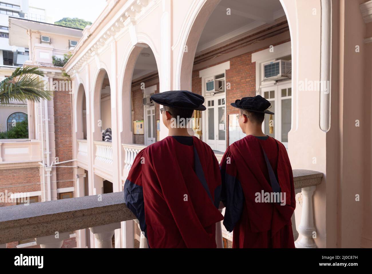 two happy proud PhD graduated male students in Academic dress gown. back view Stock Photo