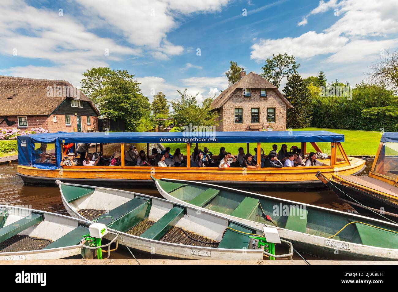 GIETHOORN, THE NETHERLANDS - JULY 26, 2016: Tourists enjoying a canal cruise with a wooden boat in the famous Dutch village of Giethoorn, The Netherla Stock Photo