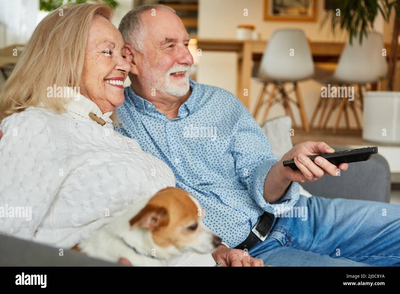 Senior couple on the sofa at home using the remote control as relaxed tv viewers Stock Photo