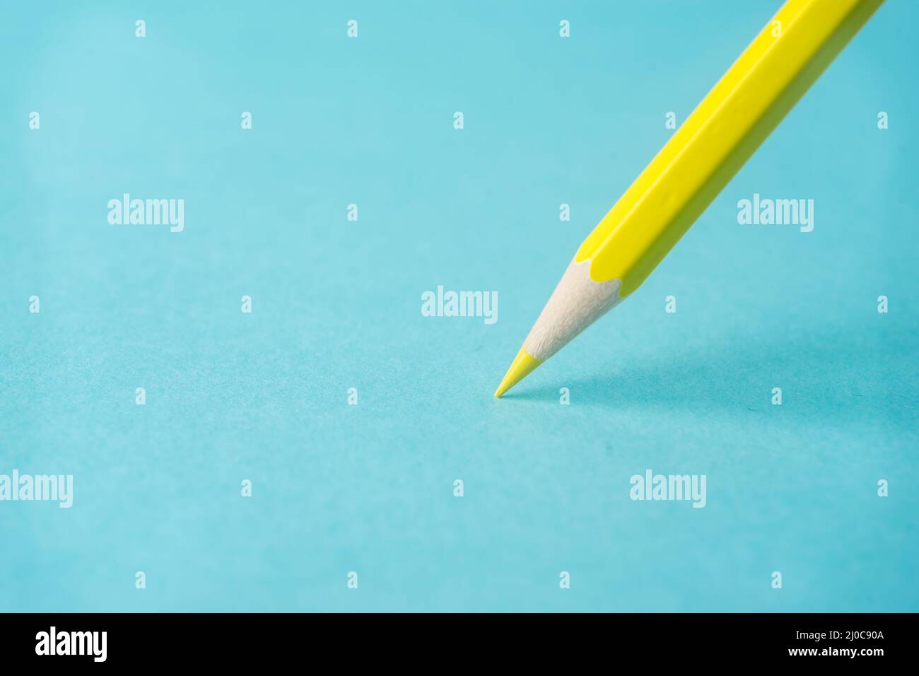 Business concept - one yellow color pencil stand on blue paper background. It's symbol of key point and confident. Stock Photo