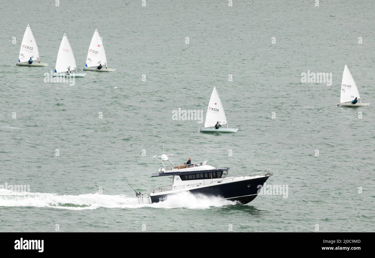 Crosshaven, Cork, Ireland. 18th March, 2022.A motor launch passes some Laser dinghies  as it heads out on a warm spring  bank holiday in Cork harbour, Ireland.  - Credit; David Creedon / Alamy Live News Stock Photo