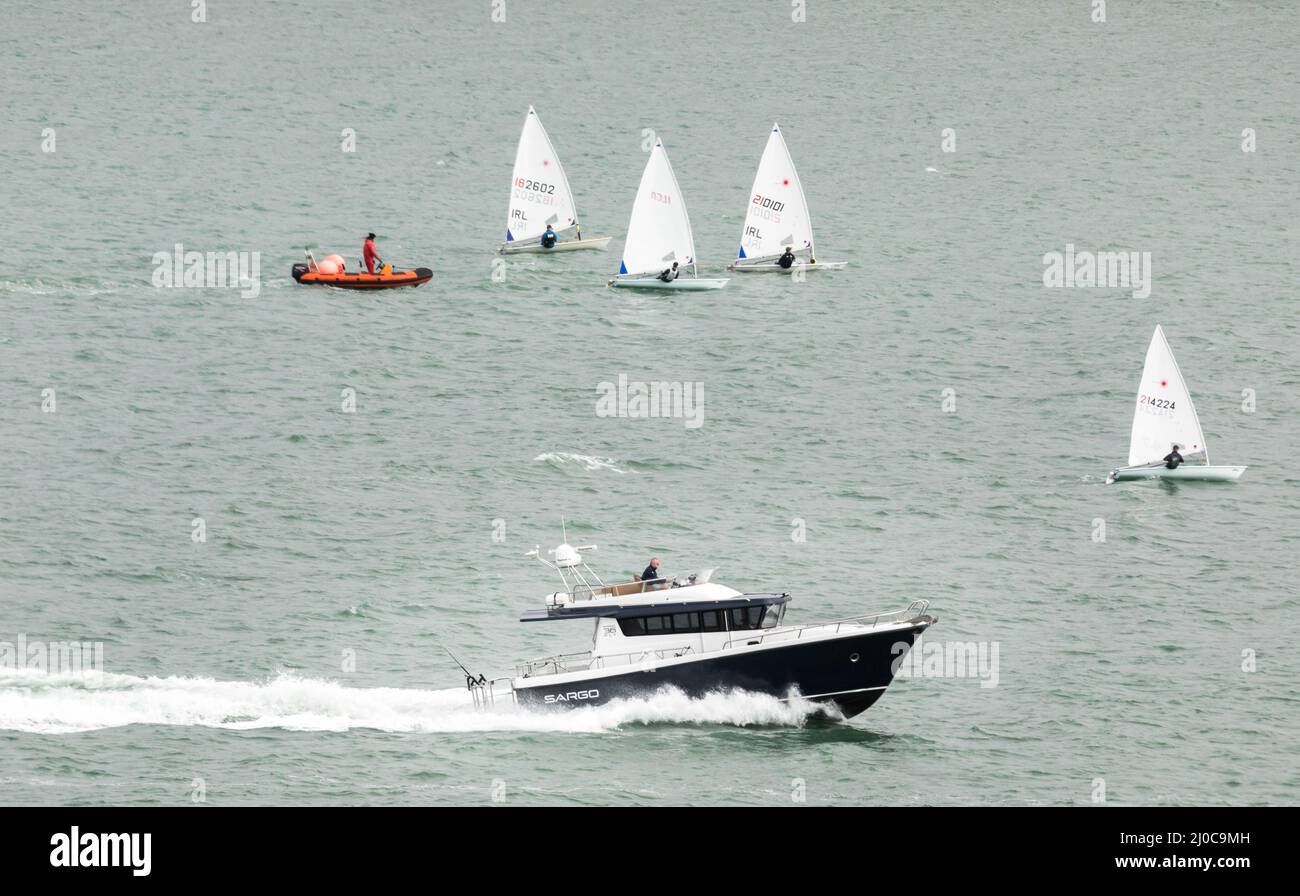 Crosshaven, Cork, Ireland. 18th March, 2022.A motor launch passes some Laser dinghies  as it heads out on a warm spring  bank holiday in Cork harbour, Ireland.  - Credit; David Creedon / Alamy Live News Stock Photo