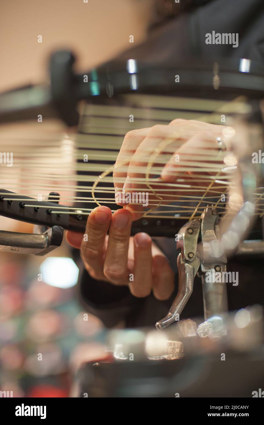 Stringing Machine. Close up of tennis stringer hands doing racket