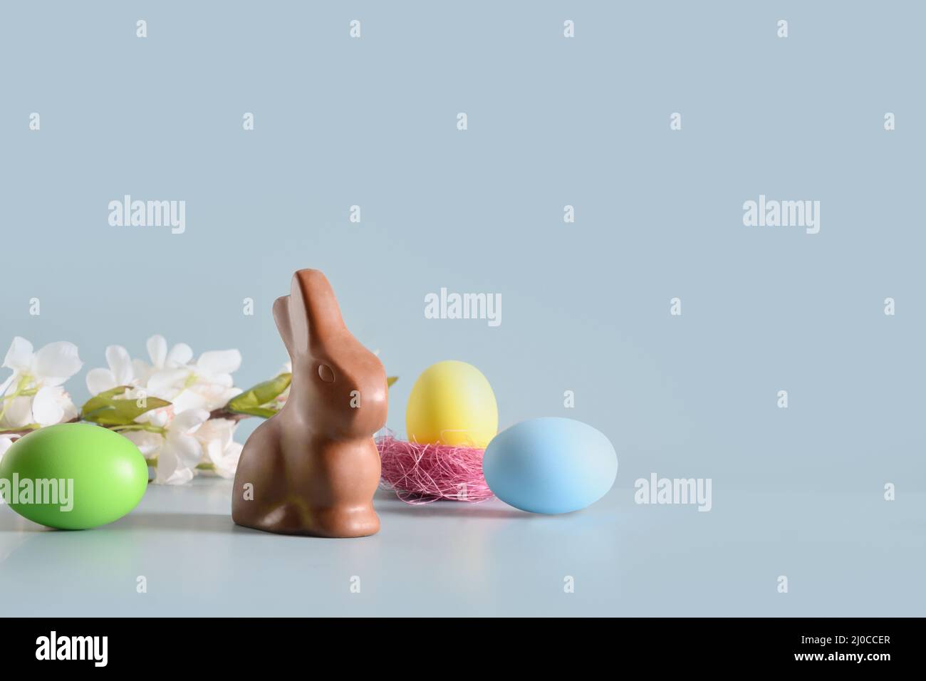 Easter chocolate rabbit in spring composition with colorful eggs on blue background. Happy Easter greeting card. Stock Photo