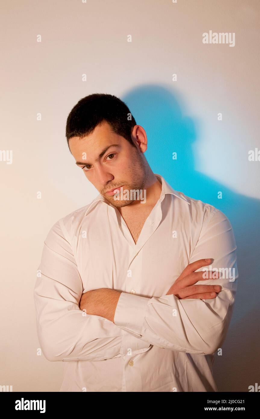 Young man crossing arms, looking at the camera. Stock Photo