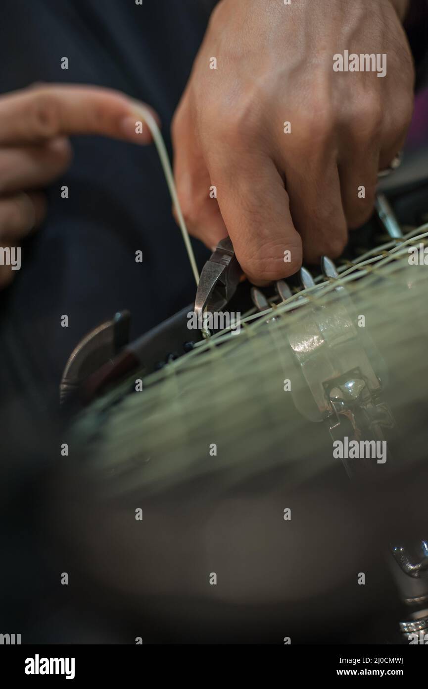 Stringing tennis racket. Tennis stringer tying knots and cutting string