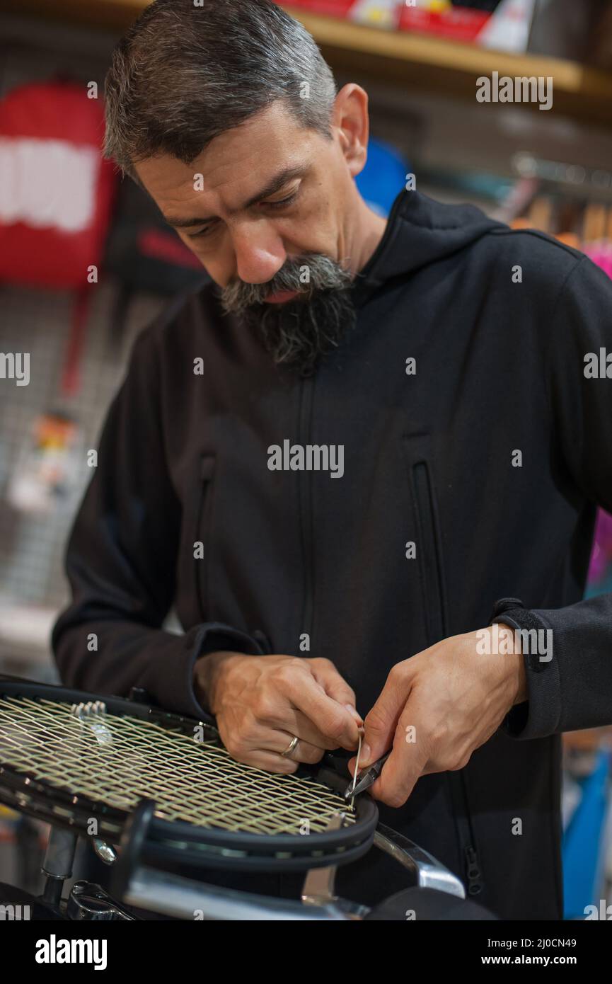 Stringing tennis racket. Tennis stringer tying knots and cutting string