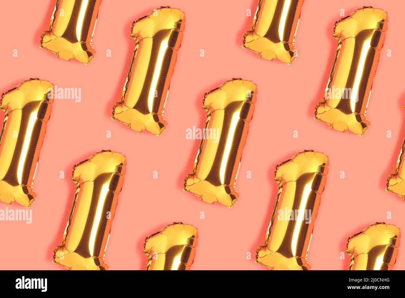 Number 1 golden balloons pattern. One year anniversary celebration concept on a coral colored background. Stock Photo