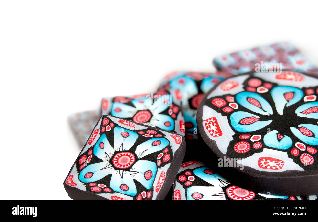 Intricate polymer clay beads made of cross sections of polymer cane. Also know as Millefiori. Blue, red and black floral designs, compressed and reduc Stock Photo