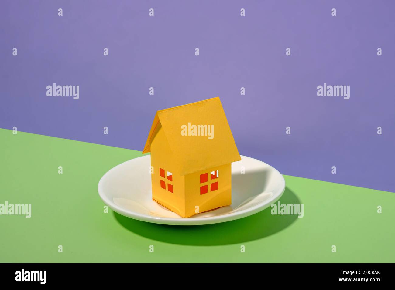 Model house served on a plate over a duo-tone green and blue background with copy space in an eco friendly housing concept Stock Photo