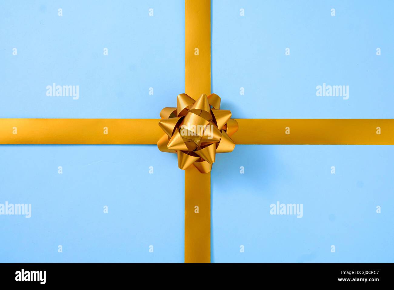 Decorative gold ribbon with a bow over blue in a gift concept for special occasions Stock Photo