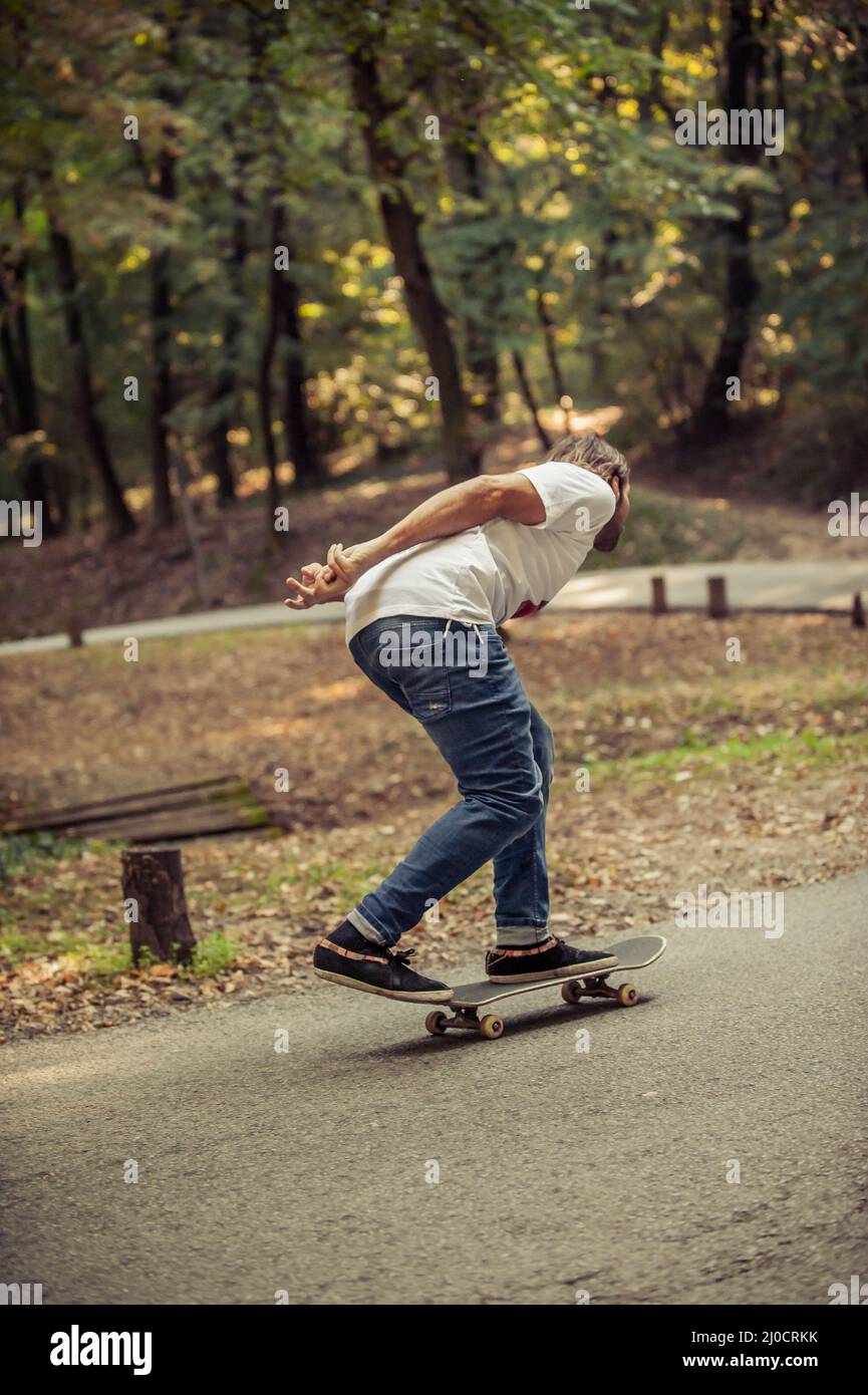Skateboarder riding a skateboard slope on the road through the forest