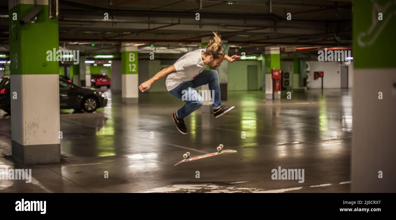Skater doing tricks and jumping in the underground garage. Urban free ride skating Stock Photo