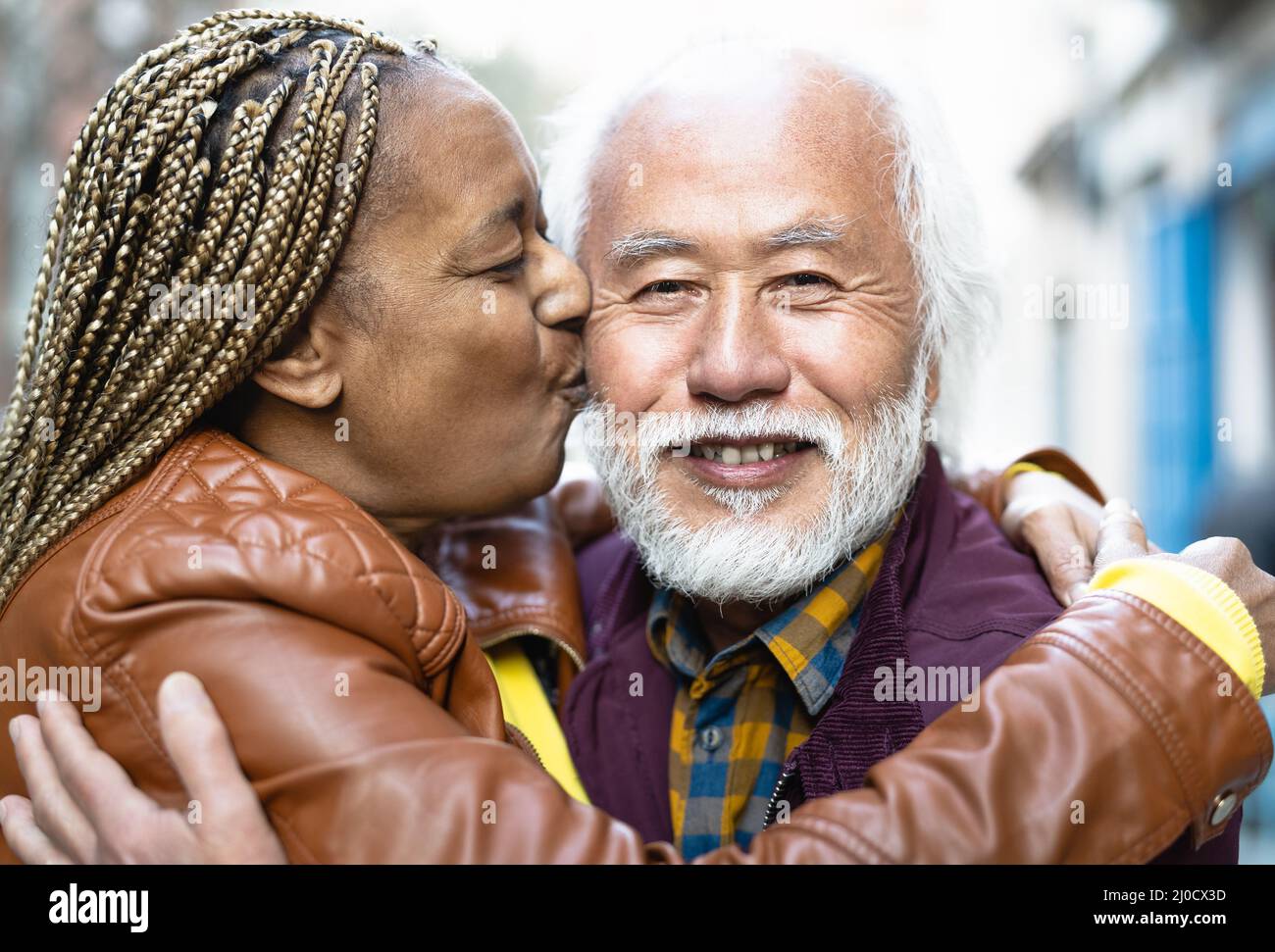 Happy multiracial senior couple having tender moments in city - Elderly people and love relationship concept Stock Photo