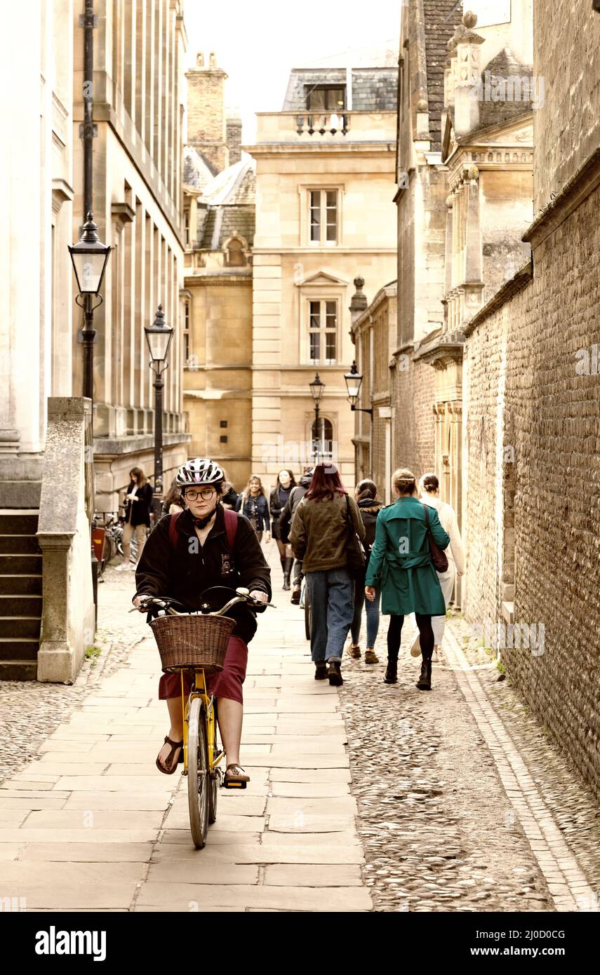 Cambridge street scene; Cambridge University student riding a bicycle, cycling in Senate House Passage, Cambridge city centre, Cambridge UK Stock Photo