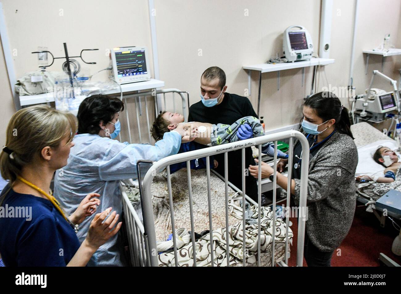 ZAPORIZHZHIA, UKRAINE - MARCH 18, 2022 - A medic puts a little boy on the bed at the Zaporizhzhia Regional Children's Clinical Hospital where children Stock Photo