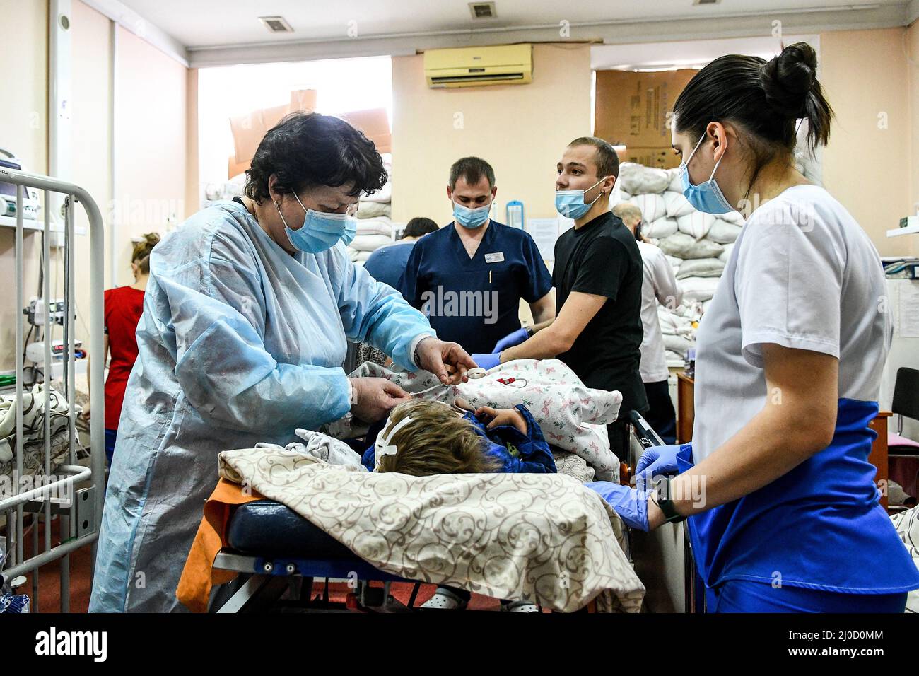 ZAPORIZHZHIA, UKRAINE - MARCH 18, 2022 - Staff members attend to a child at the Zaporizhzhia Regional Children's Clinical Hospital where children who Stock Photo