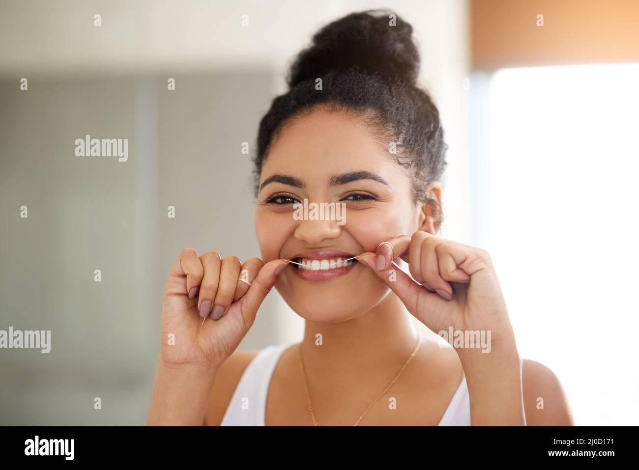Healthy habits, healthy teeth. Shot of an attractive and happy young woman flossing her teeth. Stock Photo
