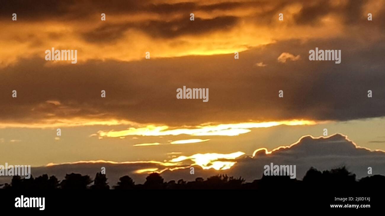 Warm Golden lined clouds at Sunset on an autumn evening Stock Photo