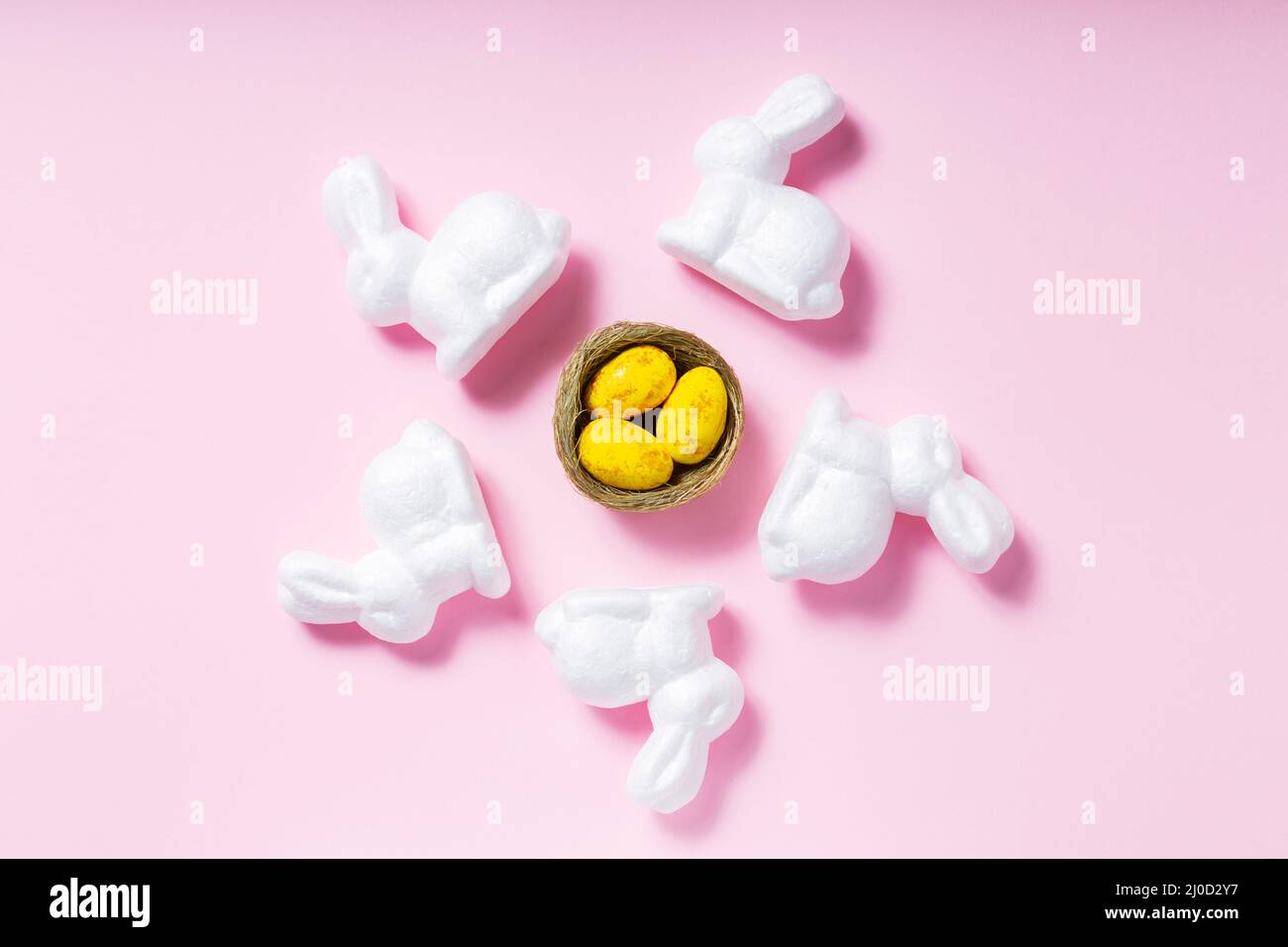 White rabbits and yellow Easter eggs on a pink background. Easter decoration concept Stock Photo