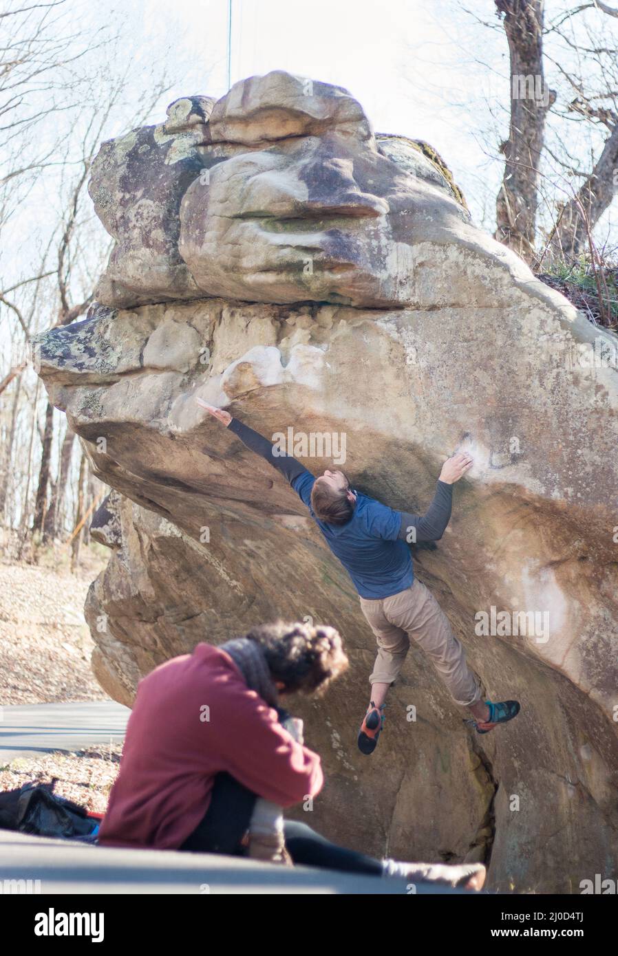Strong male rock climber jumps to complete sandstone boulder, wife filming (series) Stock Photo