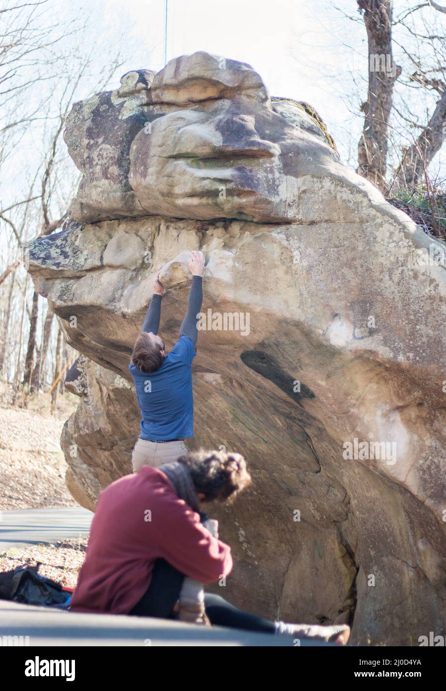 Strong male rock climber jumps to complete sandstone boulder, wife filming (series) Stock Photo