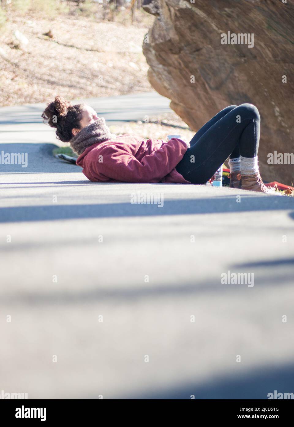 Beautiful outdoorsy woman lies on road outdoors in climbing park Stock Photo