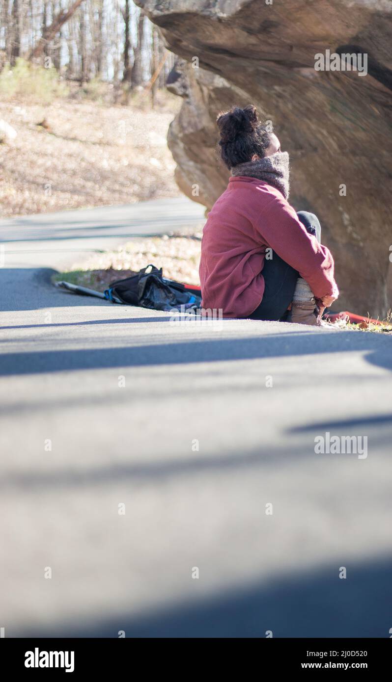 Beautiful outdoorsy woman sits on road outdoors in climbing park Stock Photo