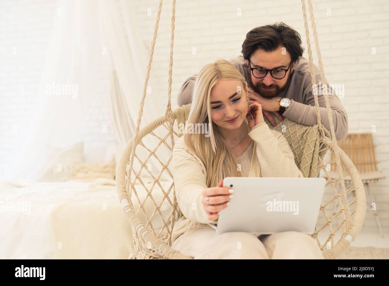 cute caucasian couple sitting on an inddor sing whilst watching a film or something else on a laptop. High quality photo Stock Photo