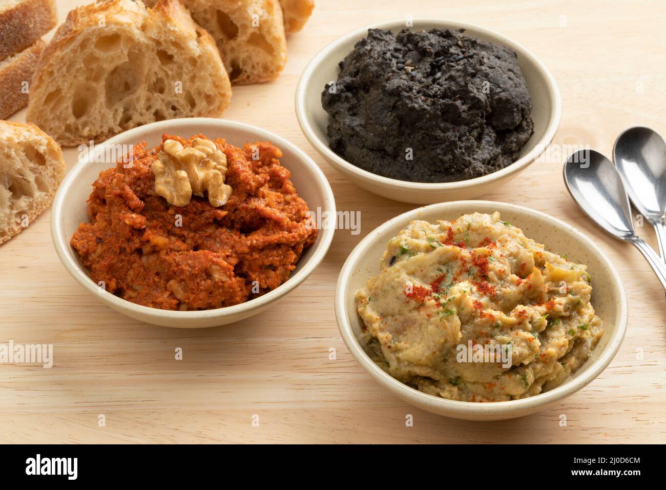Bowls with fresh home made Baba ganoush, Muhammara and black Hummus close up for appetizer Stock Photo
