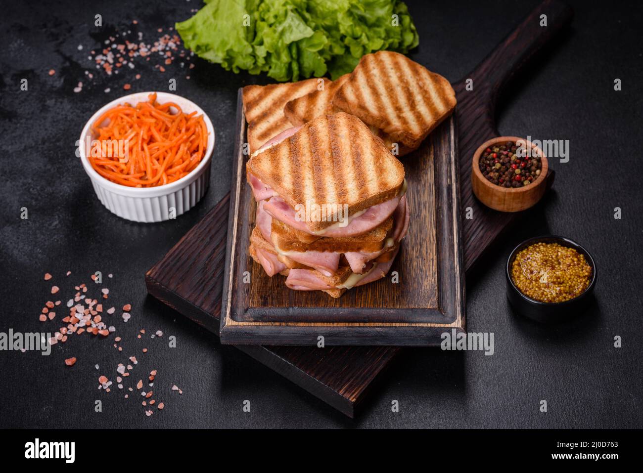 Toasted sandwiches with salami and melted cheese on black background