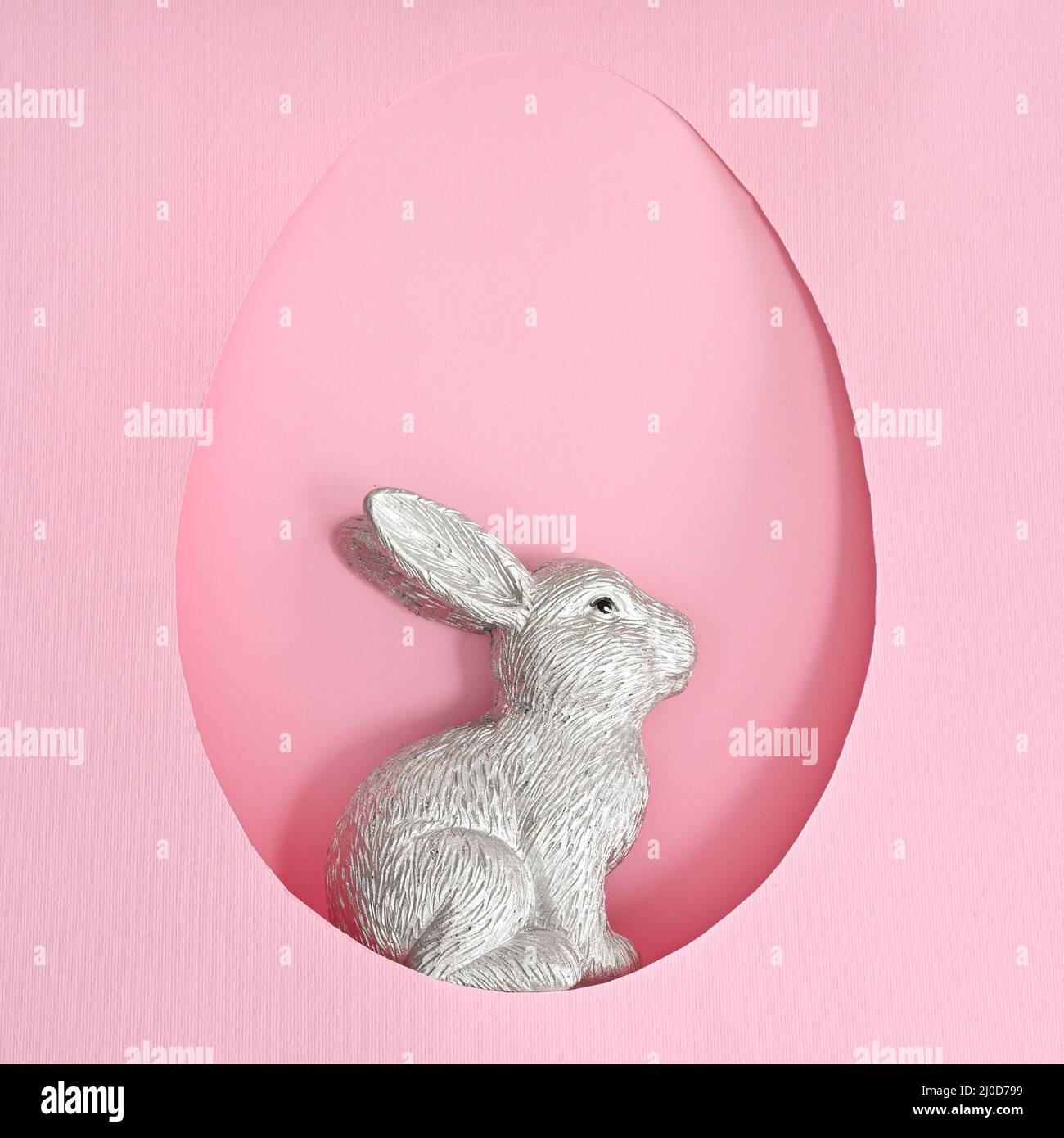 Easter ceramic bunny rabbit in egg shape frame on pastel pink background. Creative spring holidays concept Stock Photo