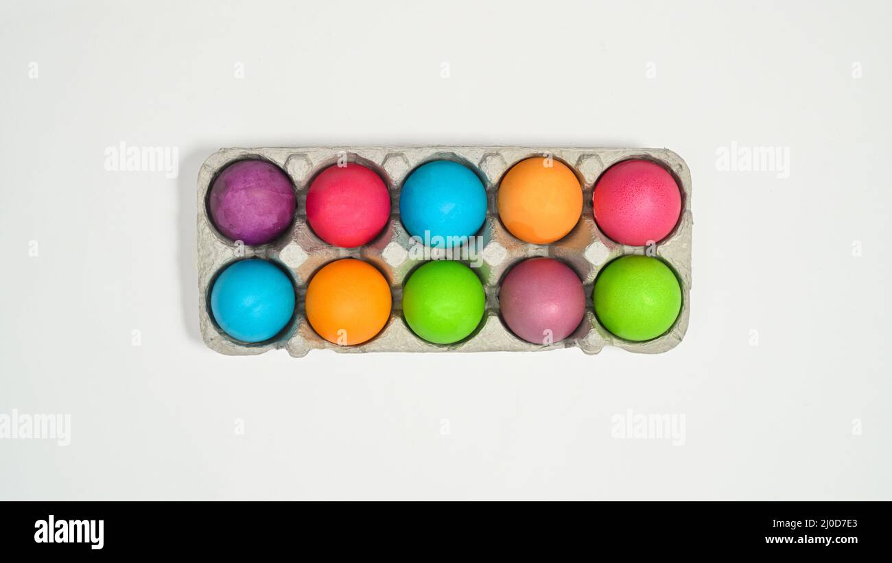 Colorful Easter eggs in card box on white background. Flat lay Stock Photo