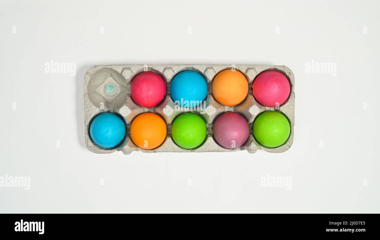 Colorful Easter eggs in card box on white background. Flat lay Stock Photo