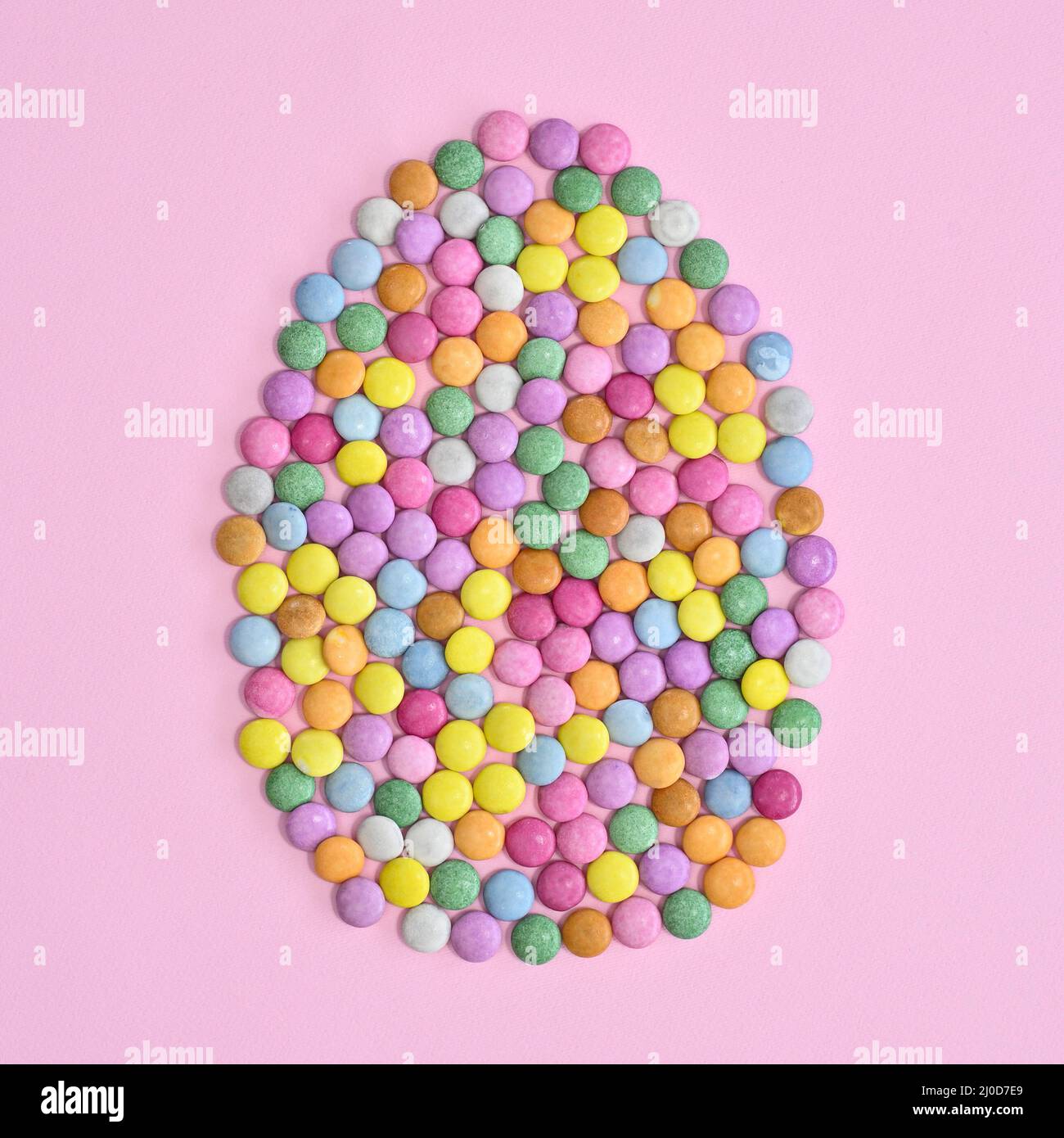 Creative Easter egg made with colorful candies on pastel pink background. Flat lay Easter concept Stock Photo